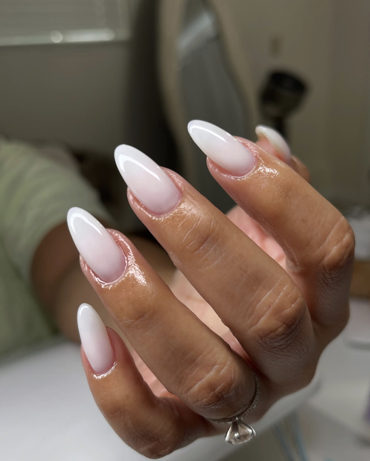 A milky white Italian manicure on long almond-shaped nails, featuring translucent polish painted with narrow unpainted sidewalls to elongate the nail plate.
