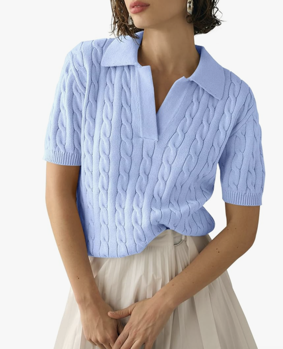 A woman wearing a light blue short-sleeve cable knit sweater with a collar and V-neckline, tucked into beige trousers.