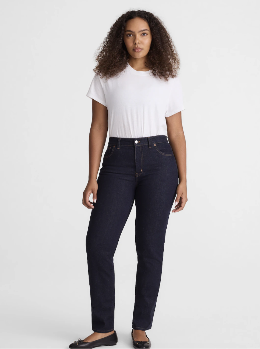 A person with an hourglass figure wearing Madewell Curvy Jules slim-straight jeans in a dark rinse wash, styled with black ballet flats to showcase the contoured waistband and tailored leg.