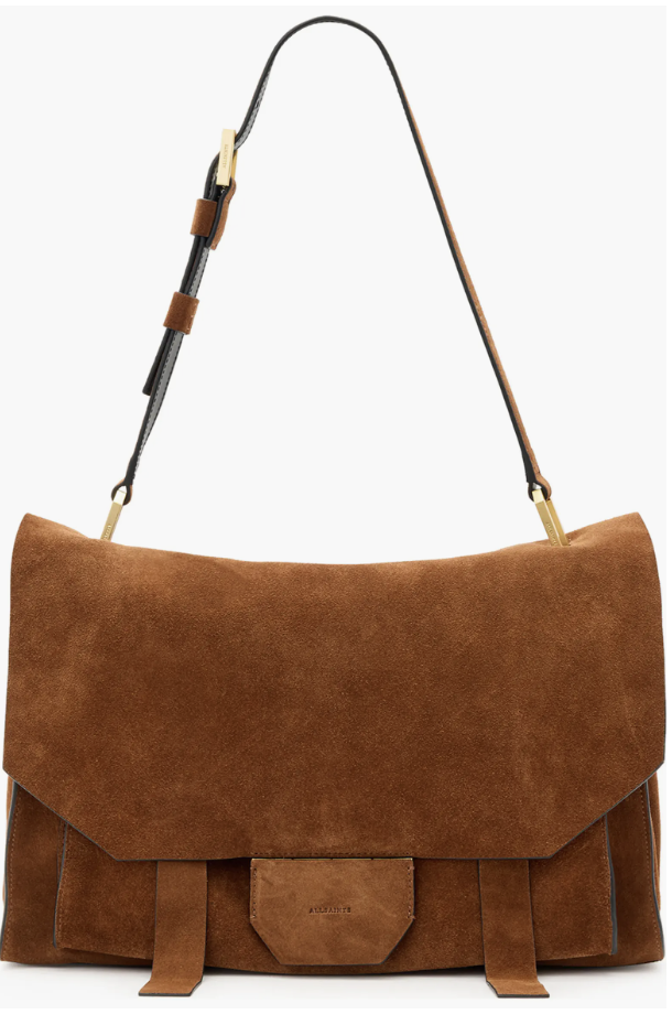 A close-up shot of the AllSaints Ursa Suede Satchel in cognac brown, showcasing its rich texture, relaxed flap closure, and matching leather shoulder strap.