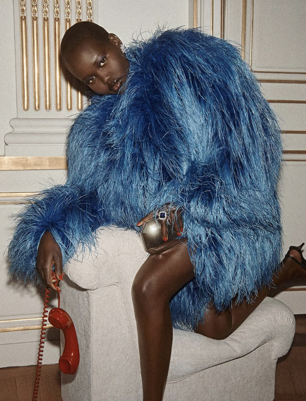 Adut Akech wearing a voluminous, textured blue faux-fur coat, illustrating how muted cool-neutral tones and a soft, velvety chroma harmonize with deep skin tones in the Soft Summer season.
