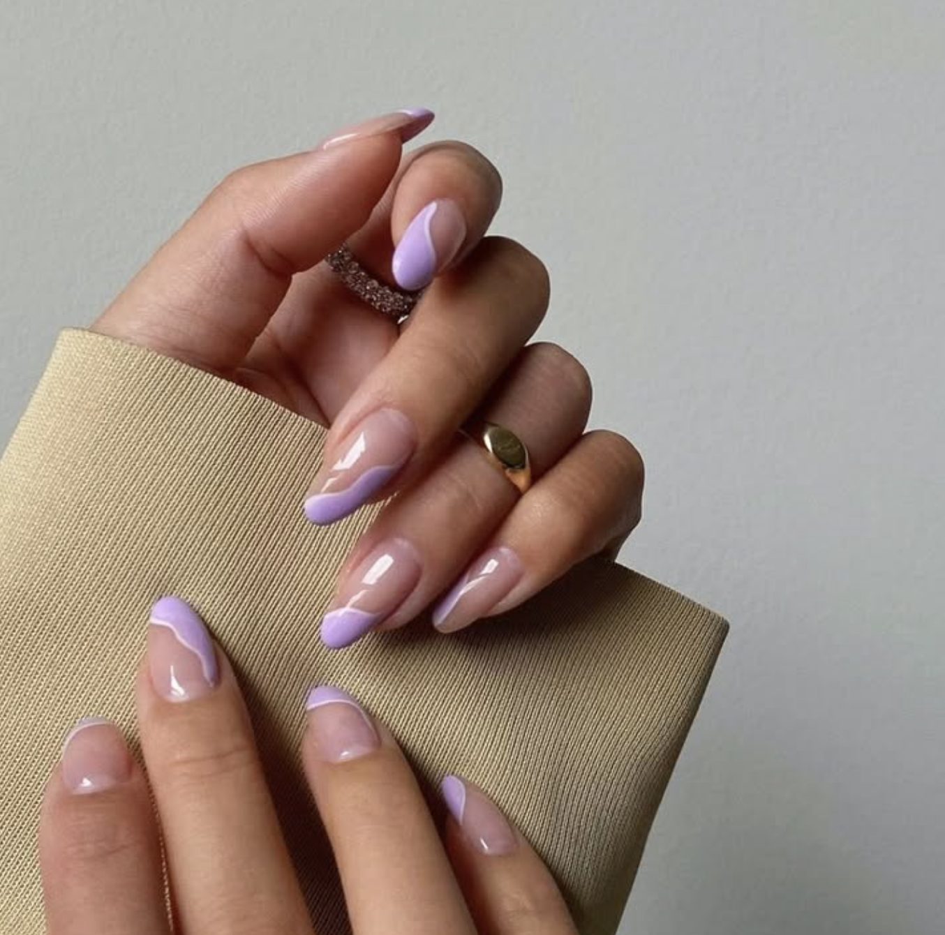 Almond-shaped nails featuring a sheer nude base with abstract light purple and white swirl designs.