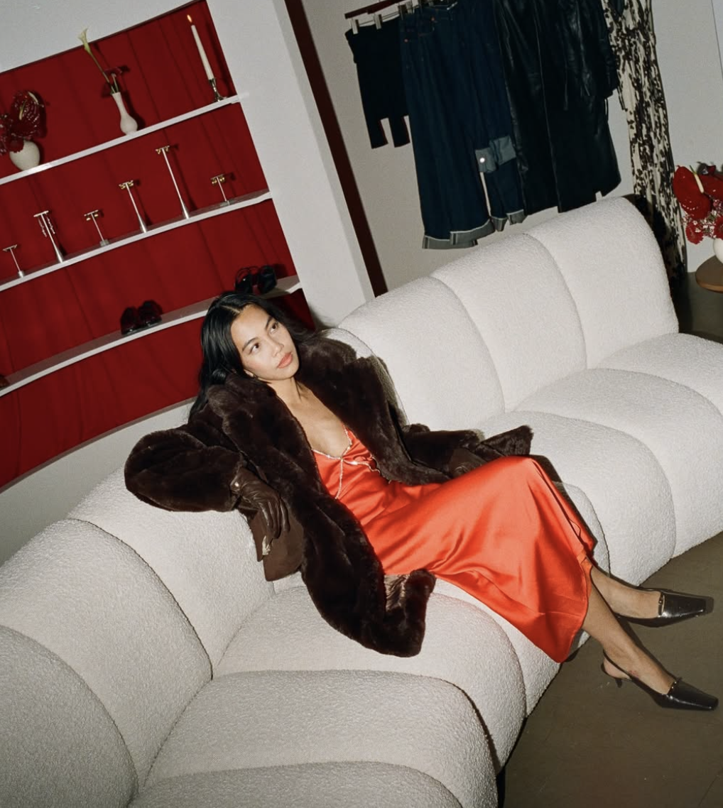 A woman in a champagne silk slip dress and black pointed-toe kitten heels.