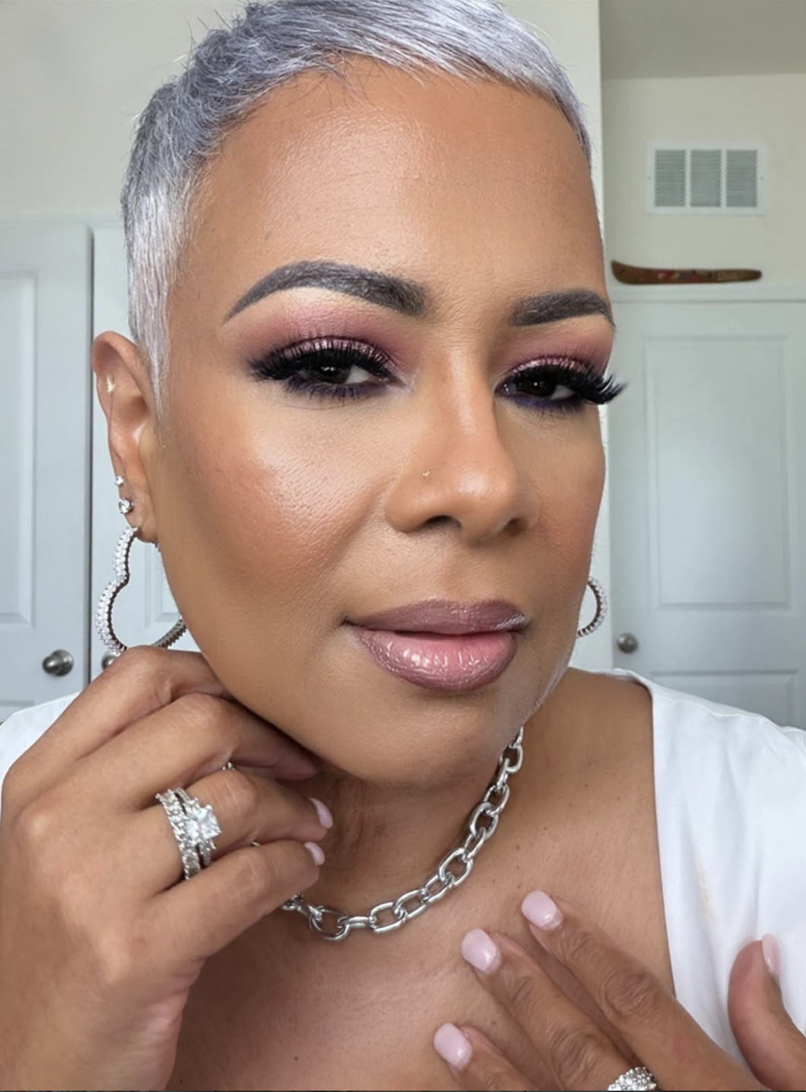 Woman with a square face wearing a very short silver pixie cut with softly textured ends.