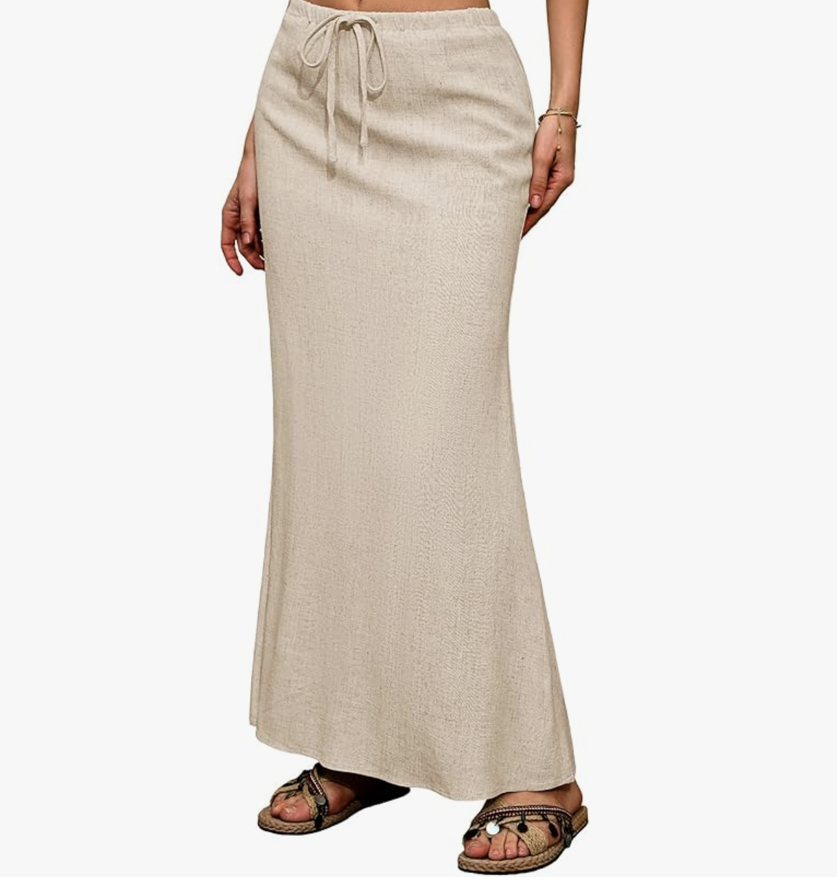 A close-up view of a person wearing a beige knitted column maxi skirt styled with flat black strappy thong sandals.