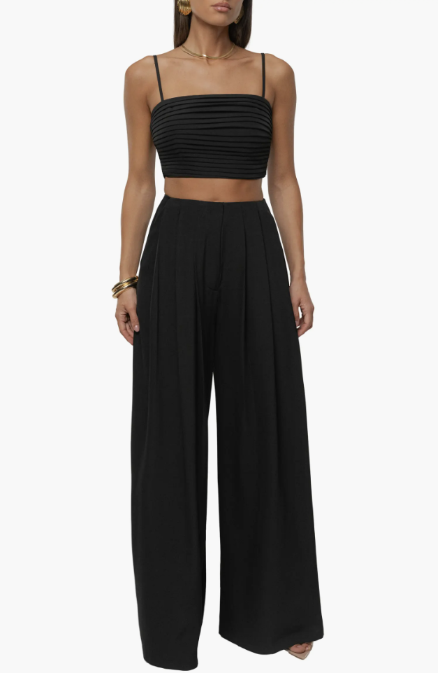 A chic monochromatic summer outfit for petite women, featuring a black pleated cropped tank top paired with matching high-waisted wide-leg trousers to visually elongate the frame.