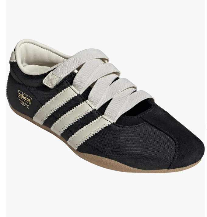 Low-profile black adidas Tokyo sneakers featuring three white stripes, a thin gum sole, and a unique wide white strap across the midfoot.