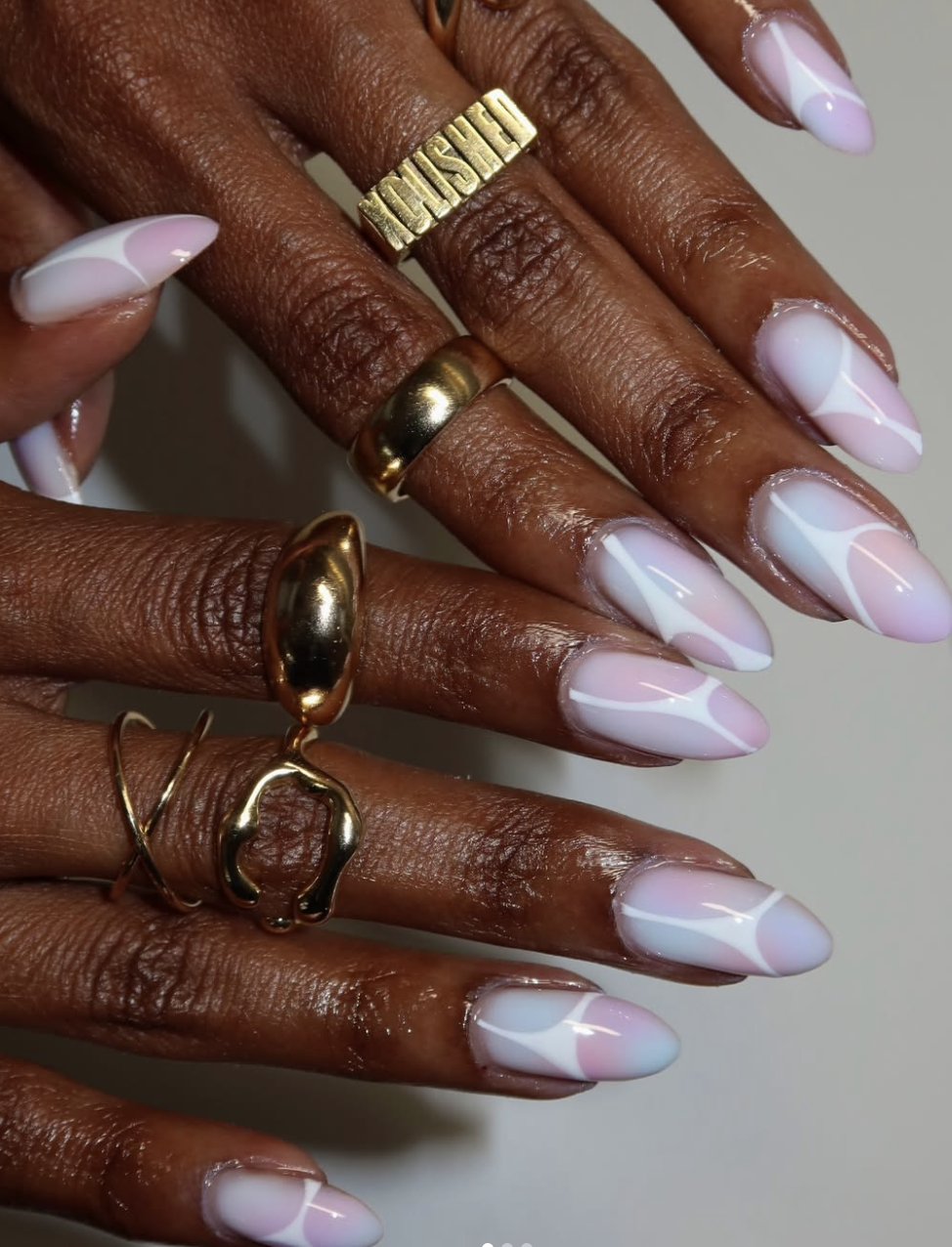 Long almond-shaped nails featuring a soft white base with a dreamy pink and lavender aura gradient effect, showcasing cute June nail ideas.