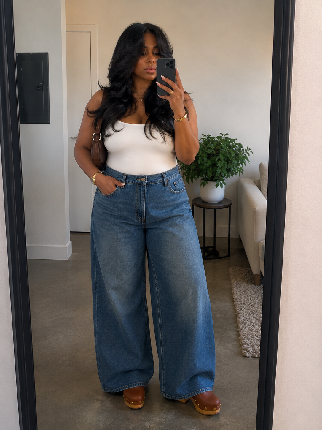 A chic everyday outfit showcasing a woman from the waist down wearing dark wash wide-leg denim jeans and tan leather platform wooden clogs.