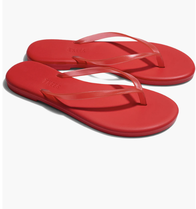 A close-up view of minimalist red leather thin-strap flip flop sandals against a white background.