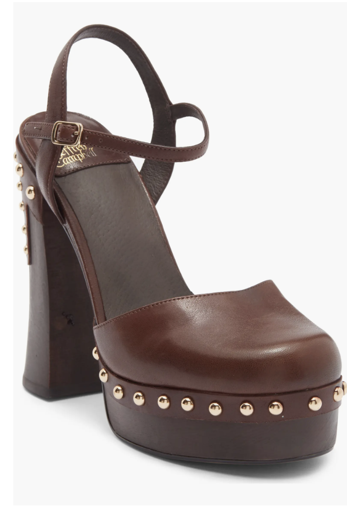 Close-up of a brown leather platform clog featuring an ankle strap, golden stud detailing, and a high block heel.