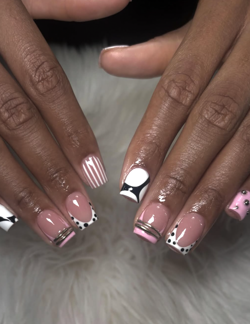 A close-up of short nails featuring a delicate pink and white fine-line checkerboard nail art pattern with silver ring accents.