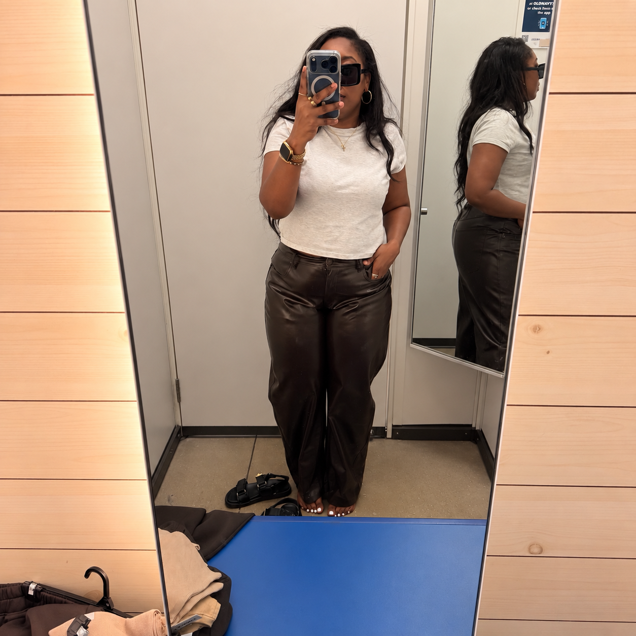 Woman in a dressing room mirror wearing Old Navy's faux-leather pants in brown, a clearance find priced at $8.97.