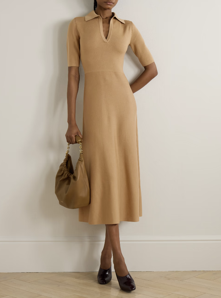 A woman wearing a sand-colored Lisa Yang Milla polo-neck cashmere midi dress, styled as a sophisticated and comfortable luxury wedding guest outfit.