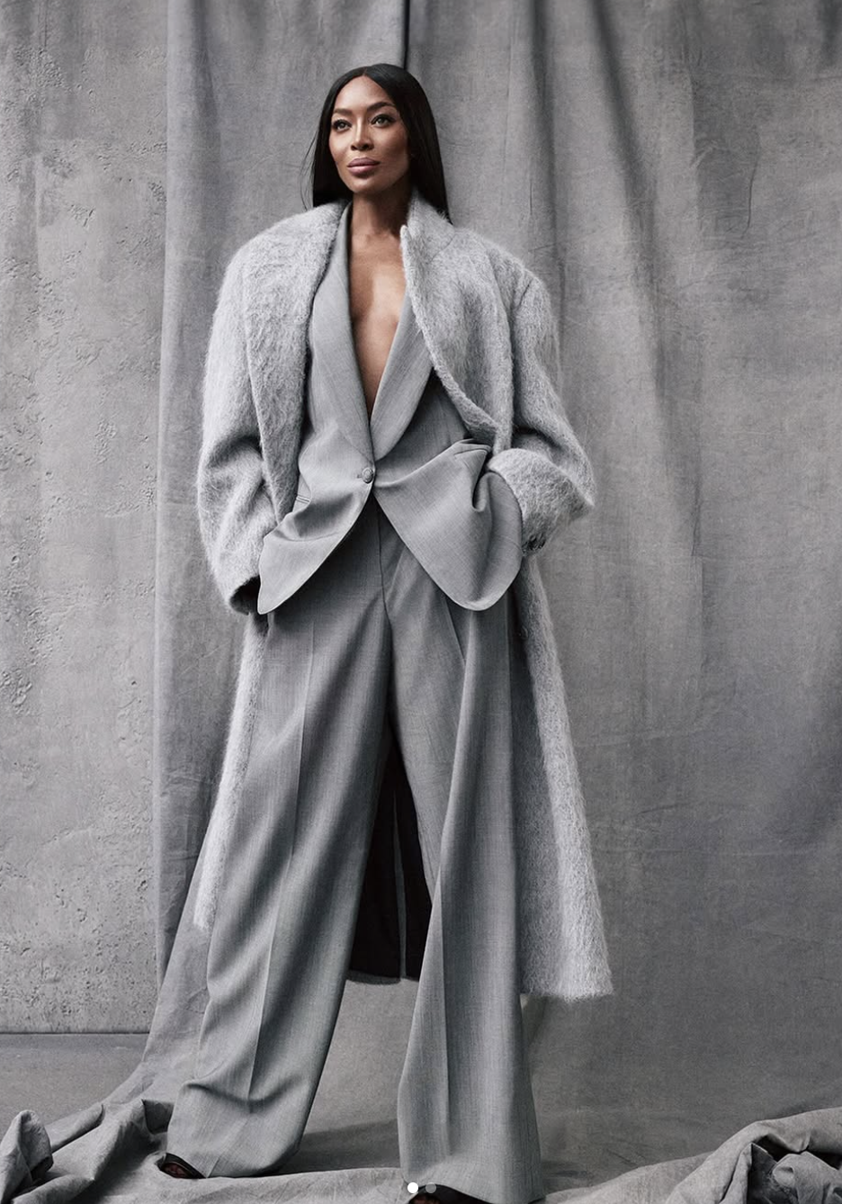 Naomi Campbell wearing a monochromatic grey power suit and a heavy textured overcoat, illustrating how high-contrast neutrals and cool, deep tones harmonize with the Deep Winter season.