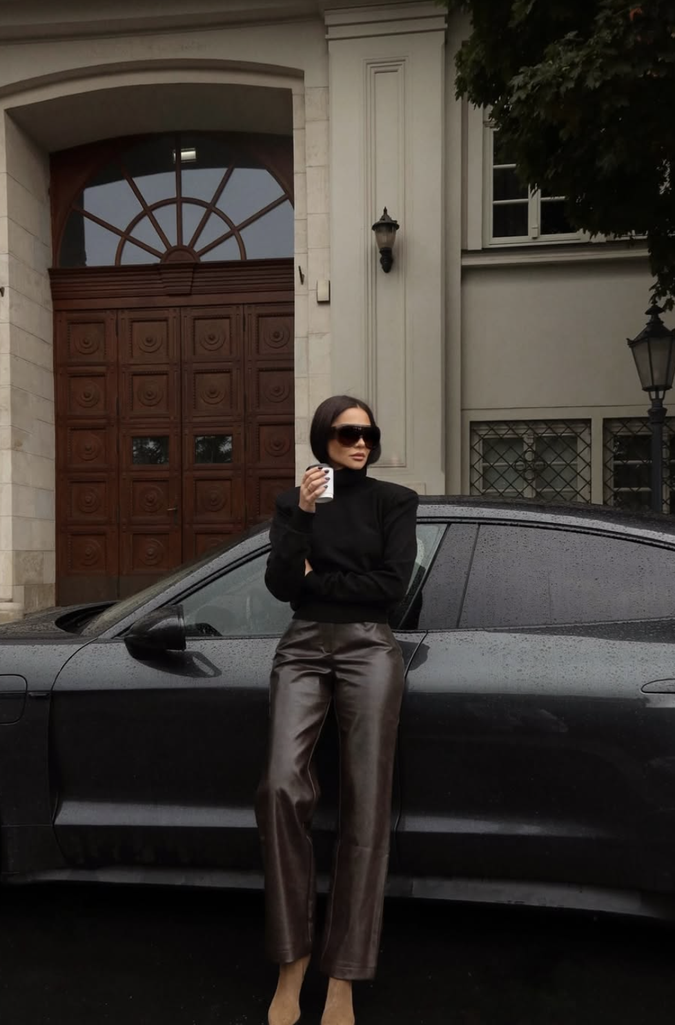 Woman wearing chocolate brown wide-leg leather pants with a black turtleneck and sunglasses