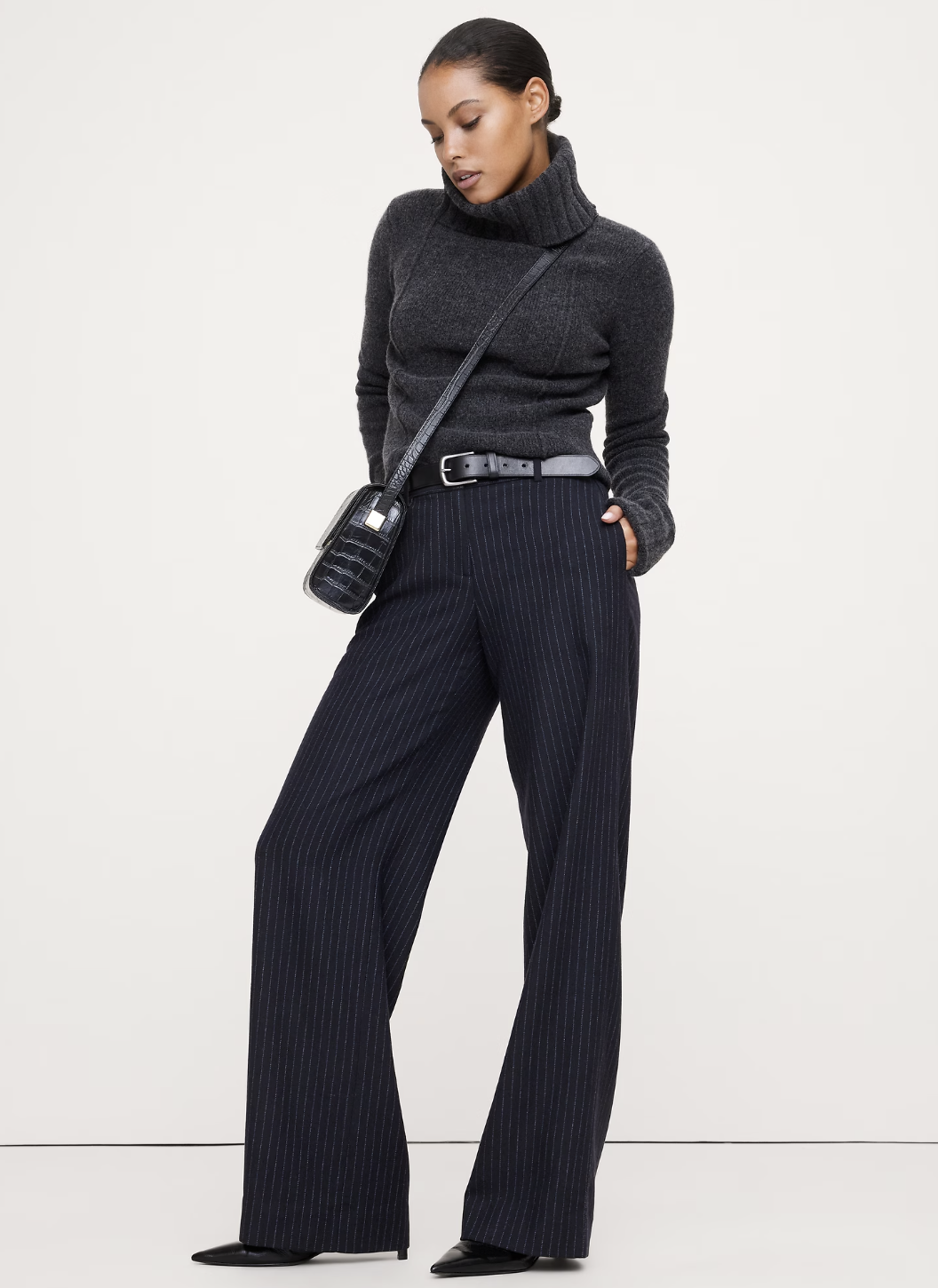 A woman wearing grey wide-leg flannel trousers with a crisp front crease.