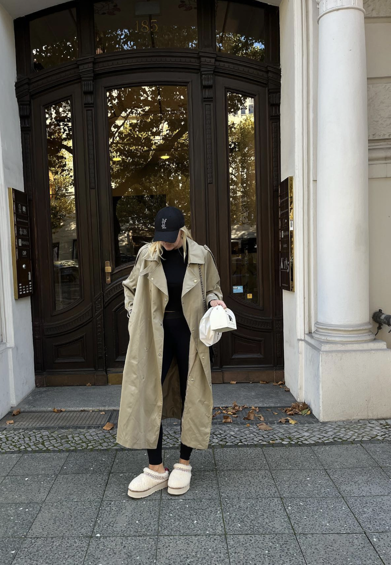 Long khaki trench with slim black bottoms, a black cap and cream platform slippers.