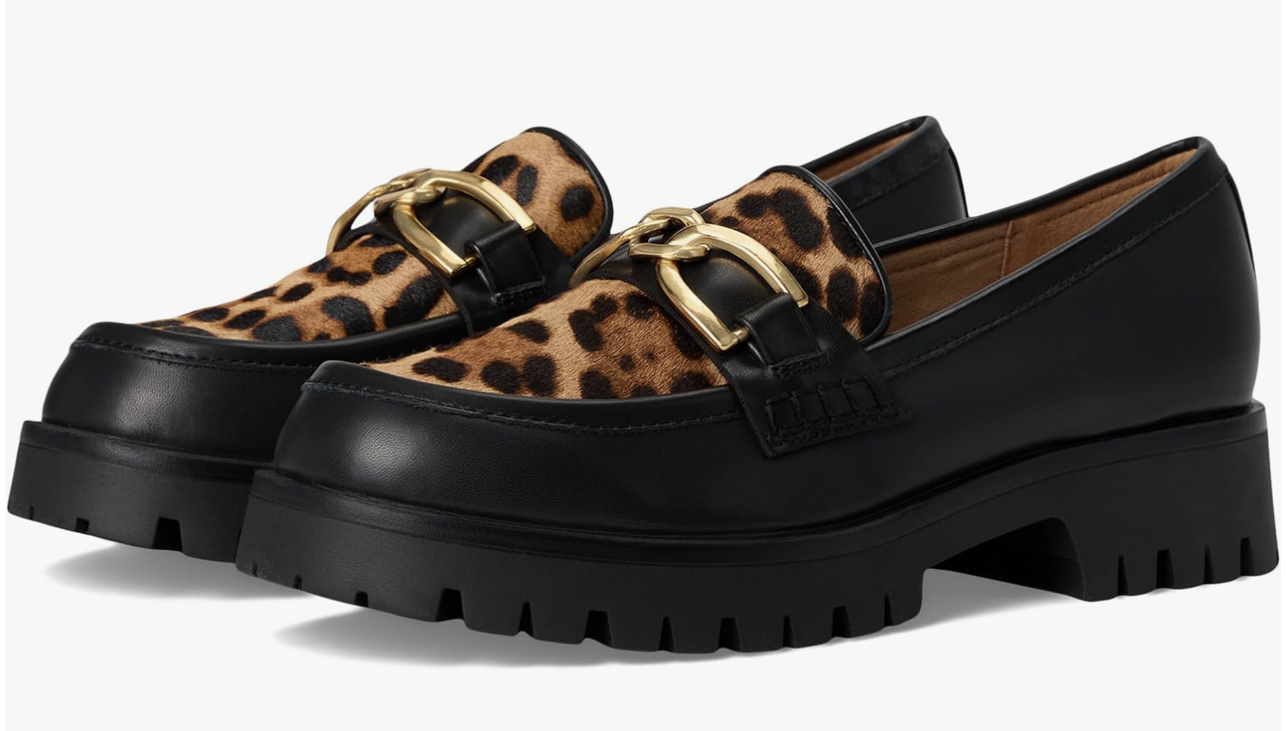 A pair of Nine West Gables chunky loafers featuring a leopard print calf hair upper, black lug soles, and a gold buckle strap across the top.