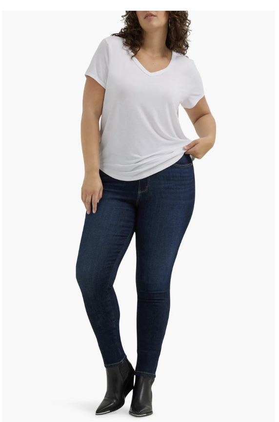 A person with an hourglass figure wearing dark wash Wrangler Bespoke high-waisted skinny jeans and black ankle boots, showing the gap-free contoured waistband and slim fit.