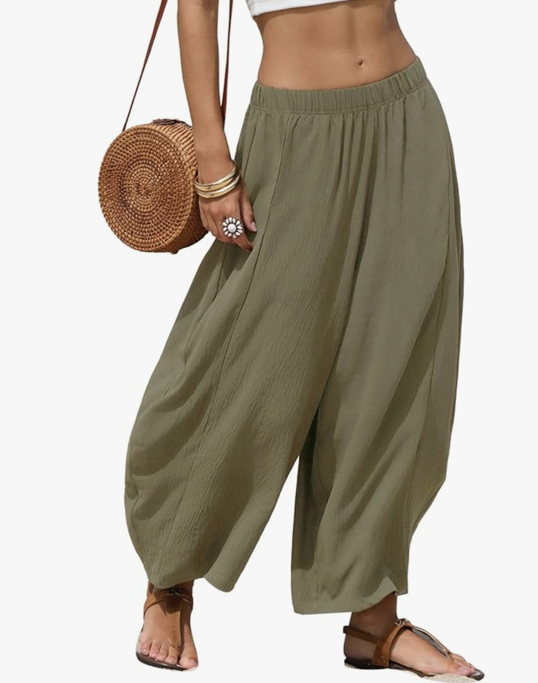 Woman wearing oversized olive green wide-leg harem pants with an elastic waistband, styled with a brown woven circle crossbody bag and sandals.
