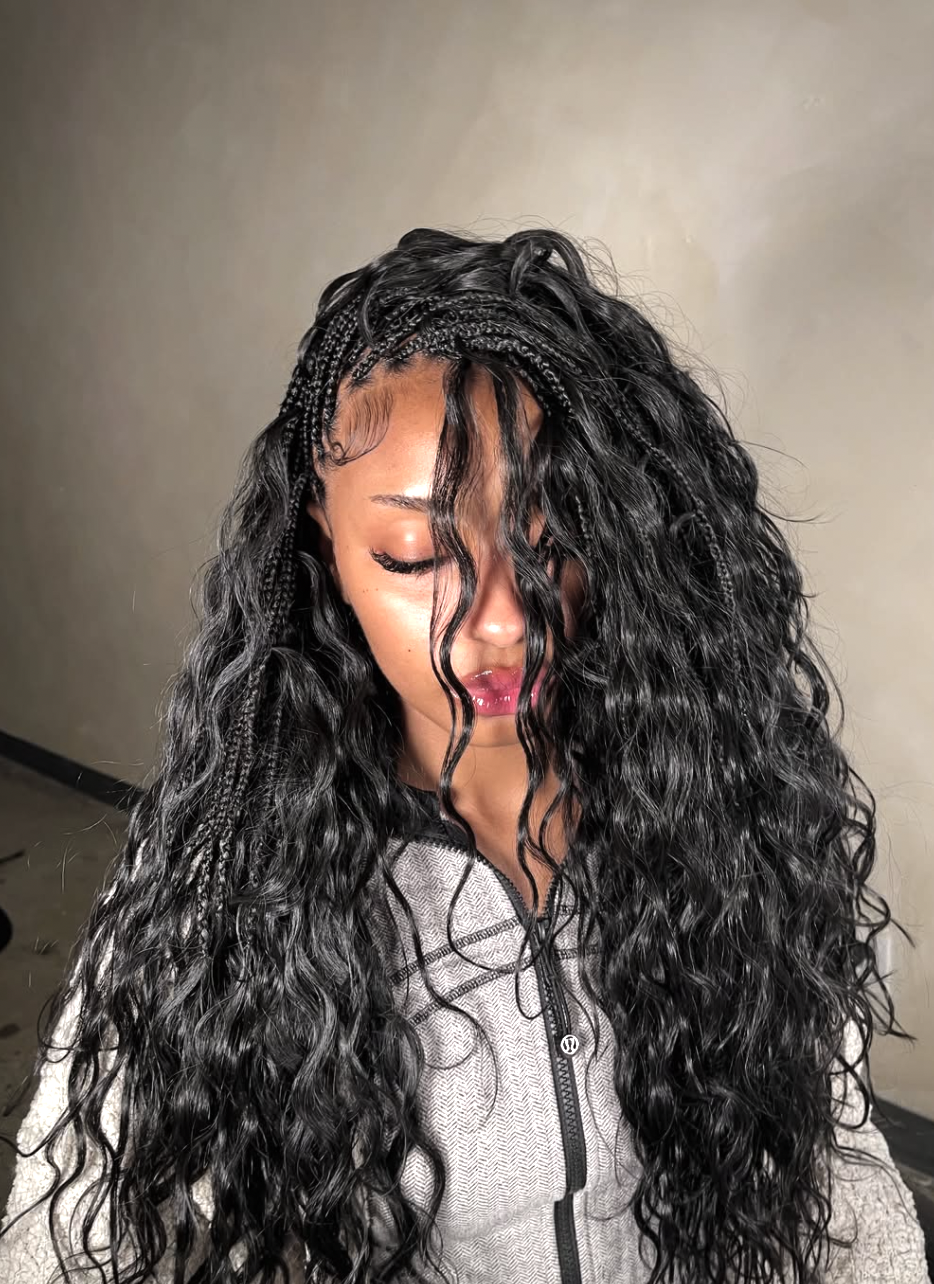 A woman with a square face shape wearing long side-part knotless braids with wavy boho ends, demonstrating how asymmetry softens a strong jawline.