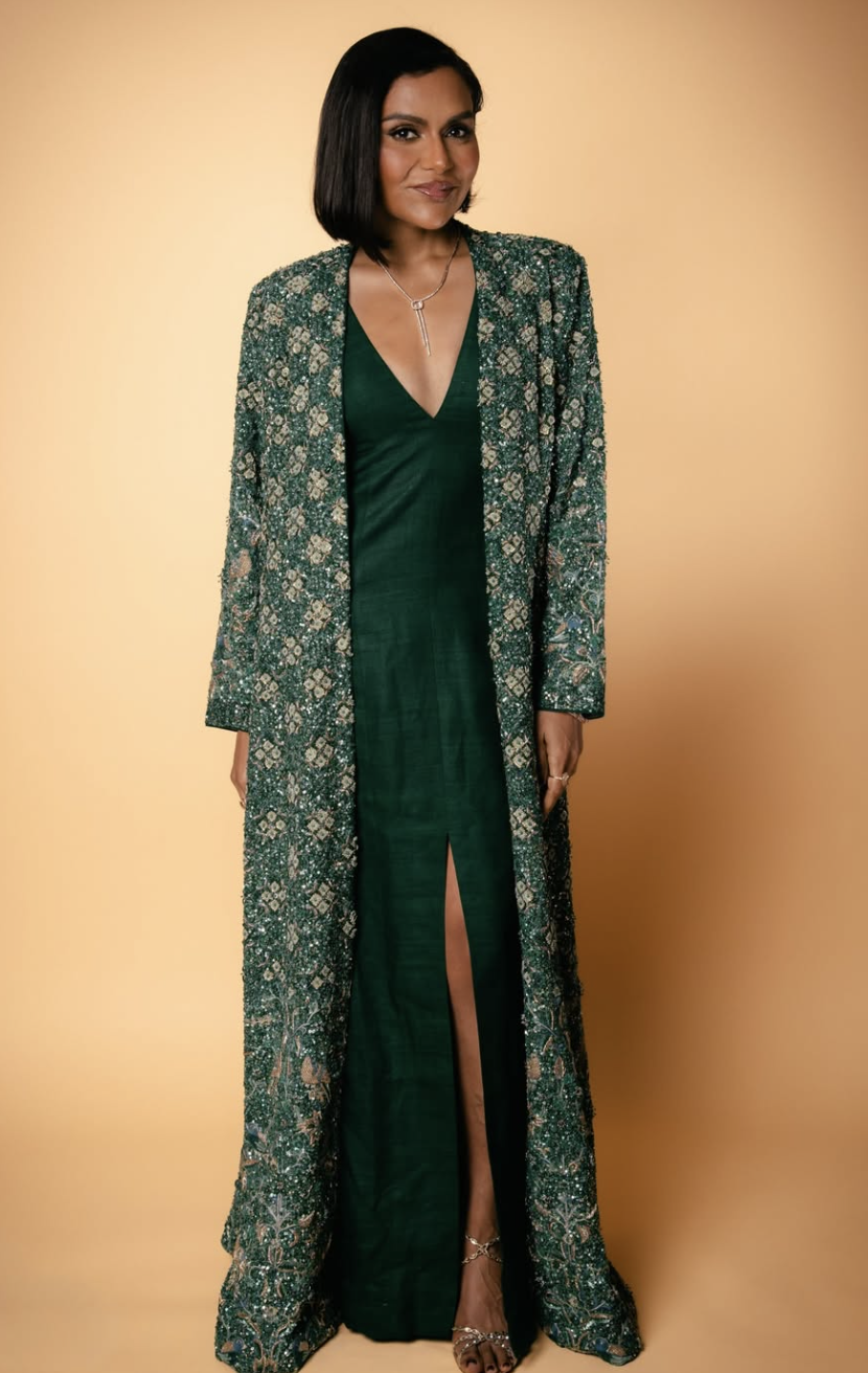 Mindy Kaling wearing a deep forest green gown and a matching patterned duster coat, illustrating how rich, earthy tones and warm-neutral undertones harmonize with the True Autumn season.