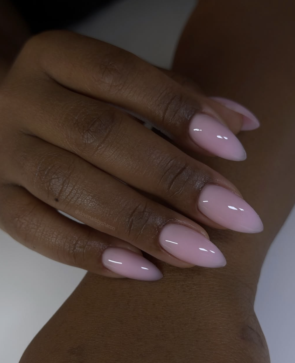 A sheer blush pink Italian manicure on short natural nails, featuring translucent polish painted with narrow unpainted sidewalls to create a clean, elongated look.