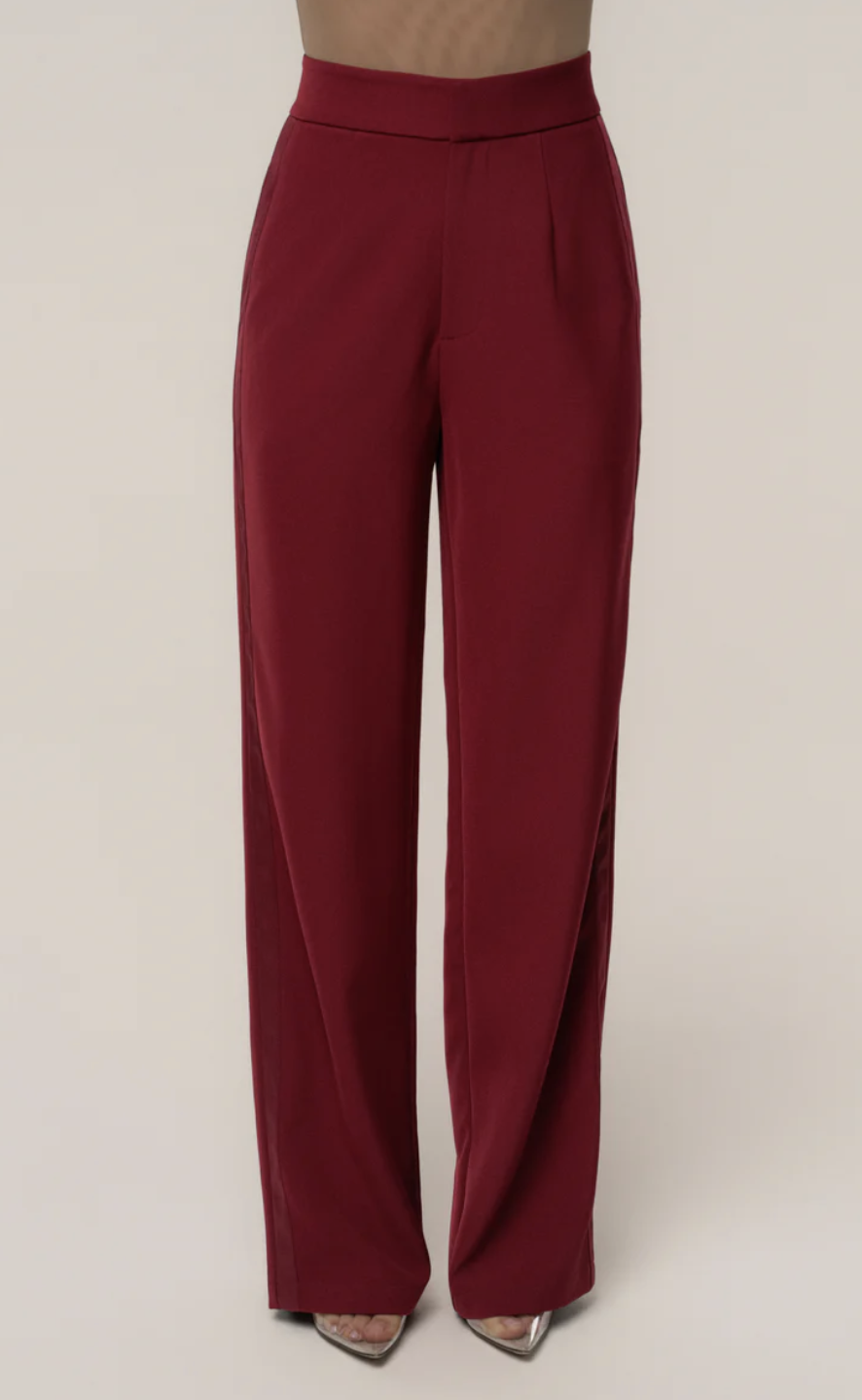 A close-up of a woman wearing burgundy high-waisted wide-leg trousers, part of a matching monochromatic blazer set for a professional power suit look.