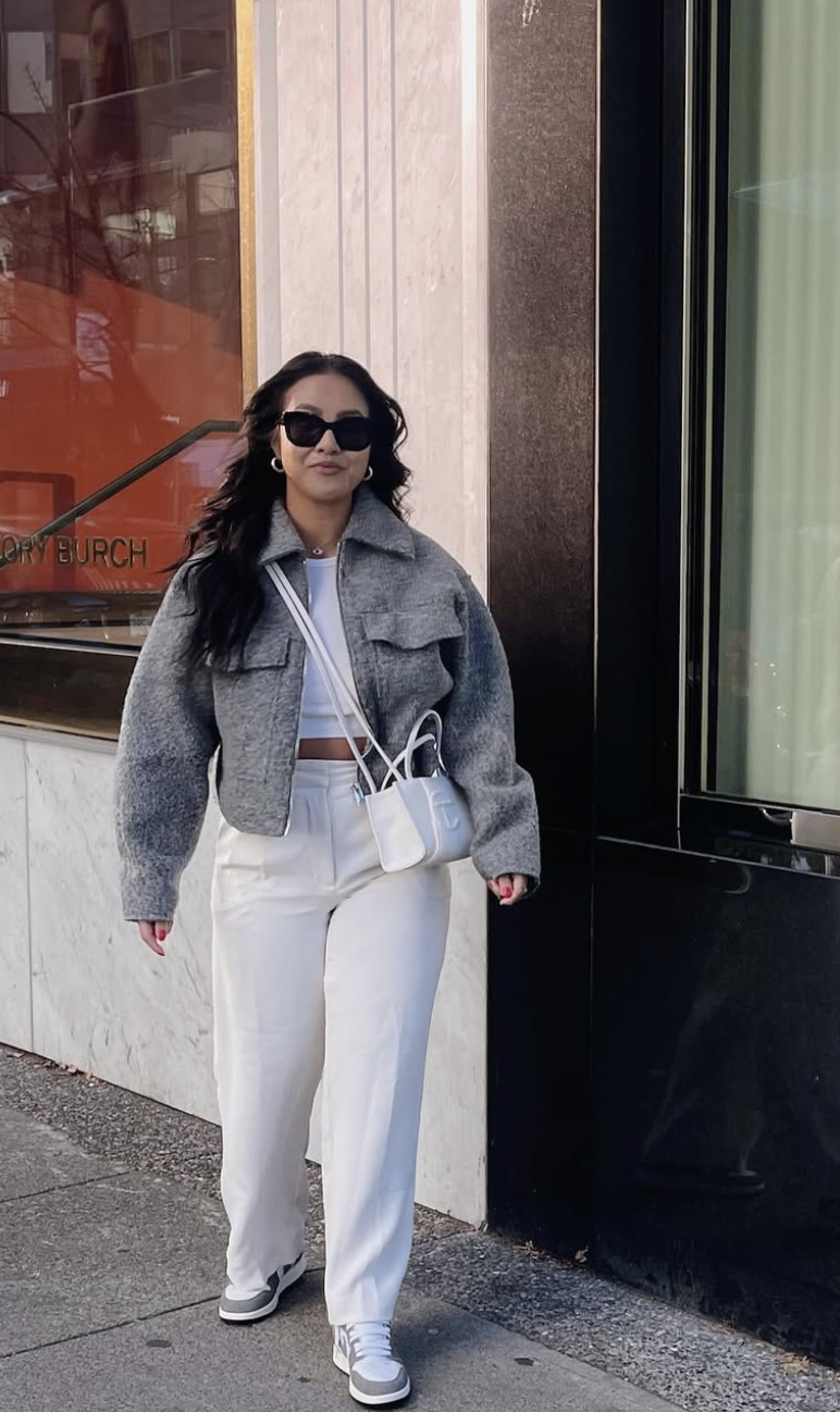 A fashion editor-approved outfit featuring high-waisted white cropped pants paired with low-profile grey and white sneakers and a grey cropped jacket, showcasing how sleek footwear maintains a clean leg line with shorter hems.