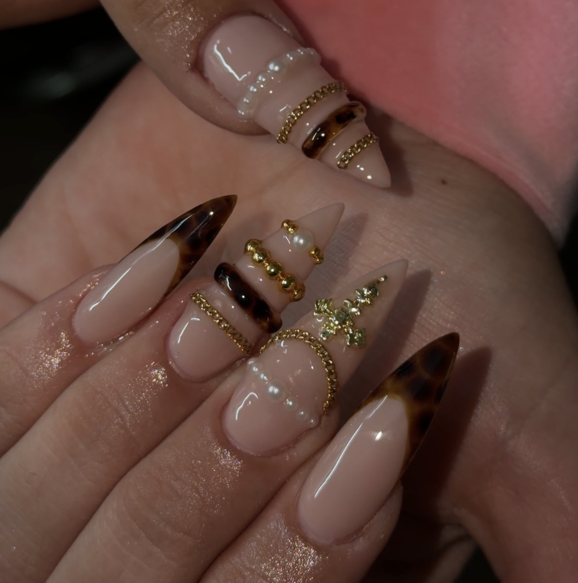 Long almond nails with a neutral base and 3D sculpted gold and silver chrome bands resembling stacked bracelets.
