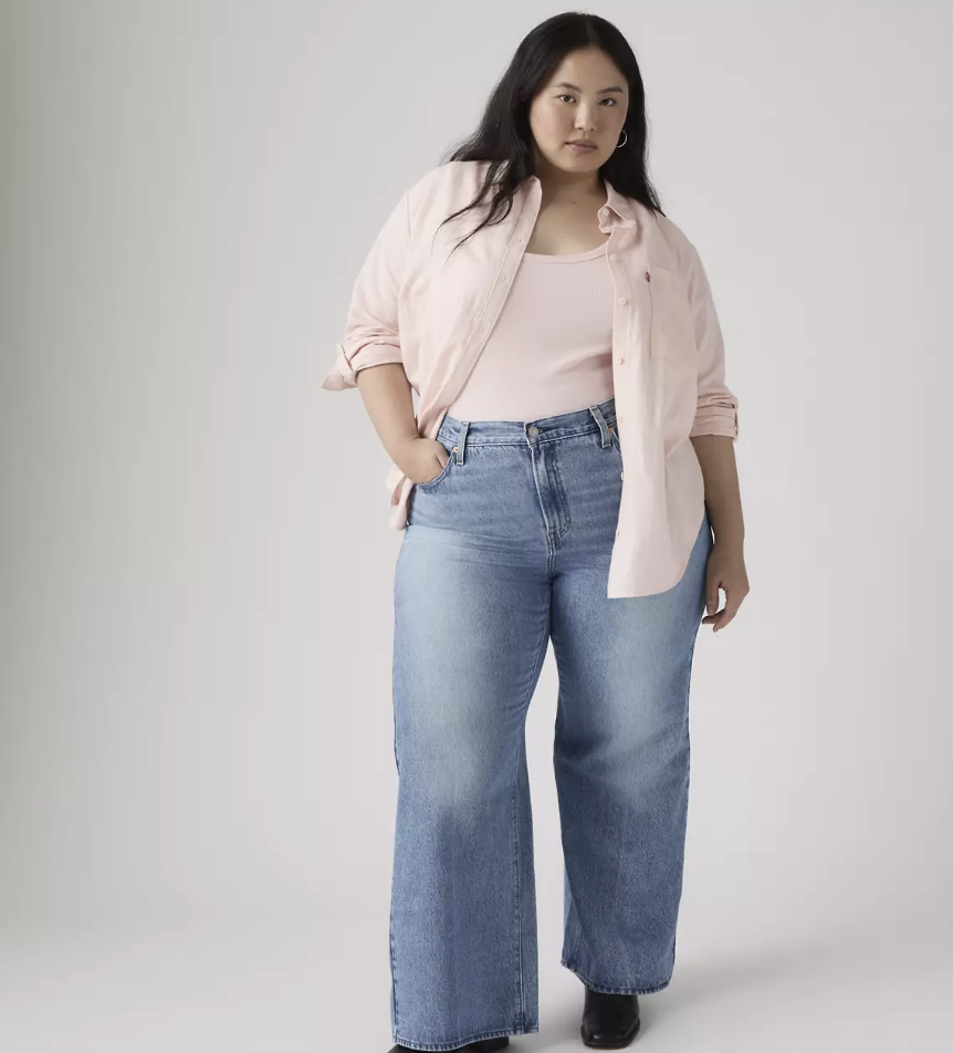A person with an hourglass figure wearing Levi's Ribcage wide-leg jeans in a light wash, showing how the high-rise waist fits securely without gapping.