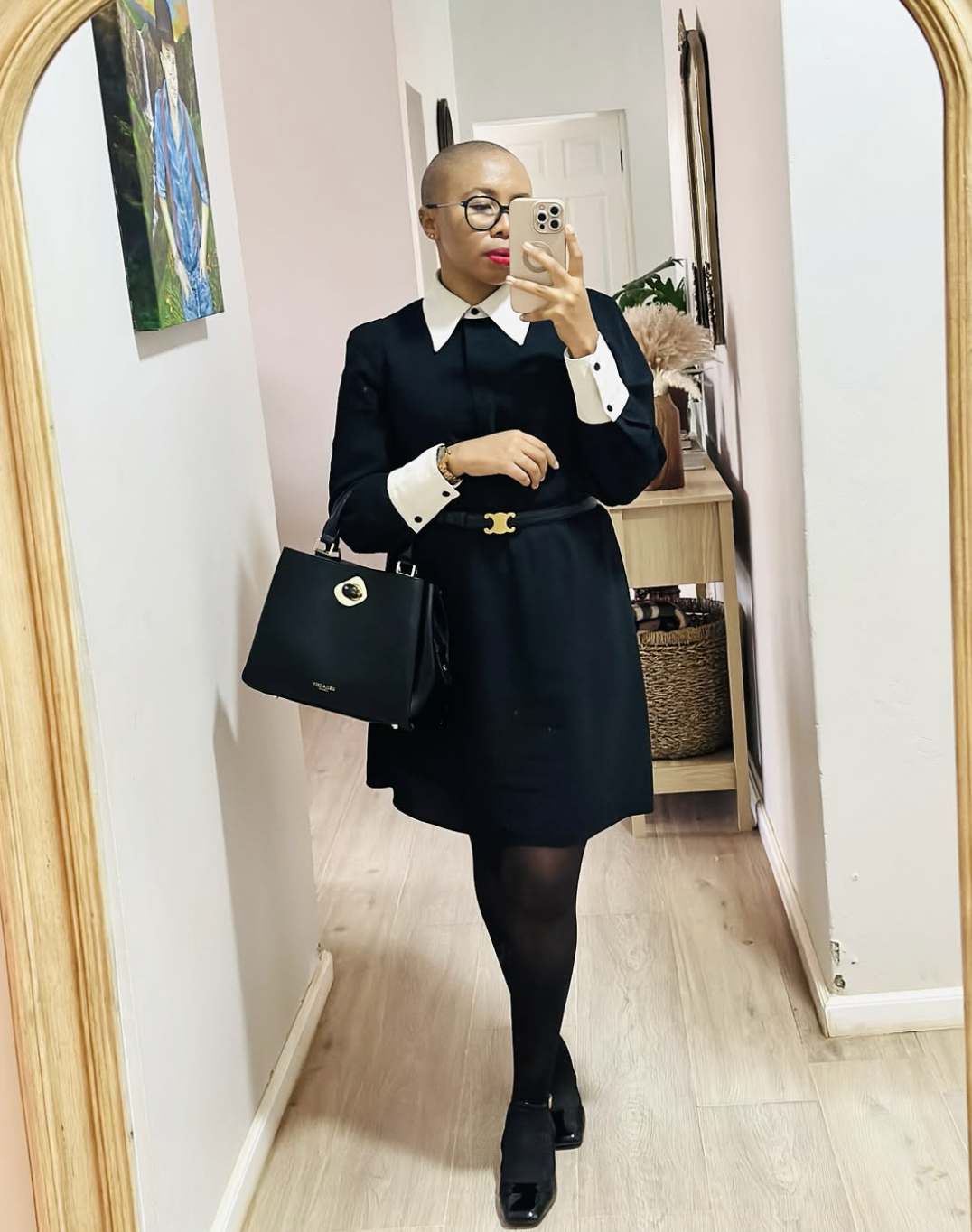 A woman wearing a navy blue mini dress with a white contrast collar and cuffs, styled with black tights and black patent Mary Jane flats for women.