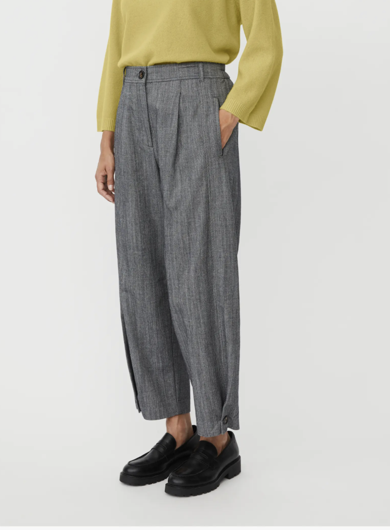 A fashion editor-approved styling guide on what shoes to wear with cropped pants, featuring grey barrel-leg trousers paired with chunky black leather loafers for a modern, structured silhouette.