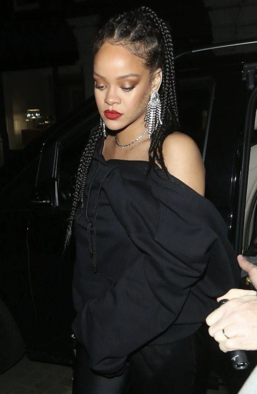 Rihanna with long, dark box braids featuring a side part, wearing a black off-the-shoulder top and statement silver earrings to show how length and side-swept hair balance a heart face shape.