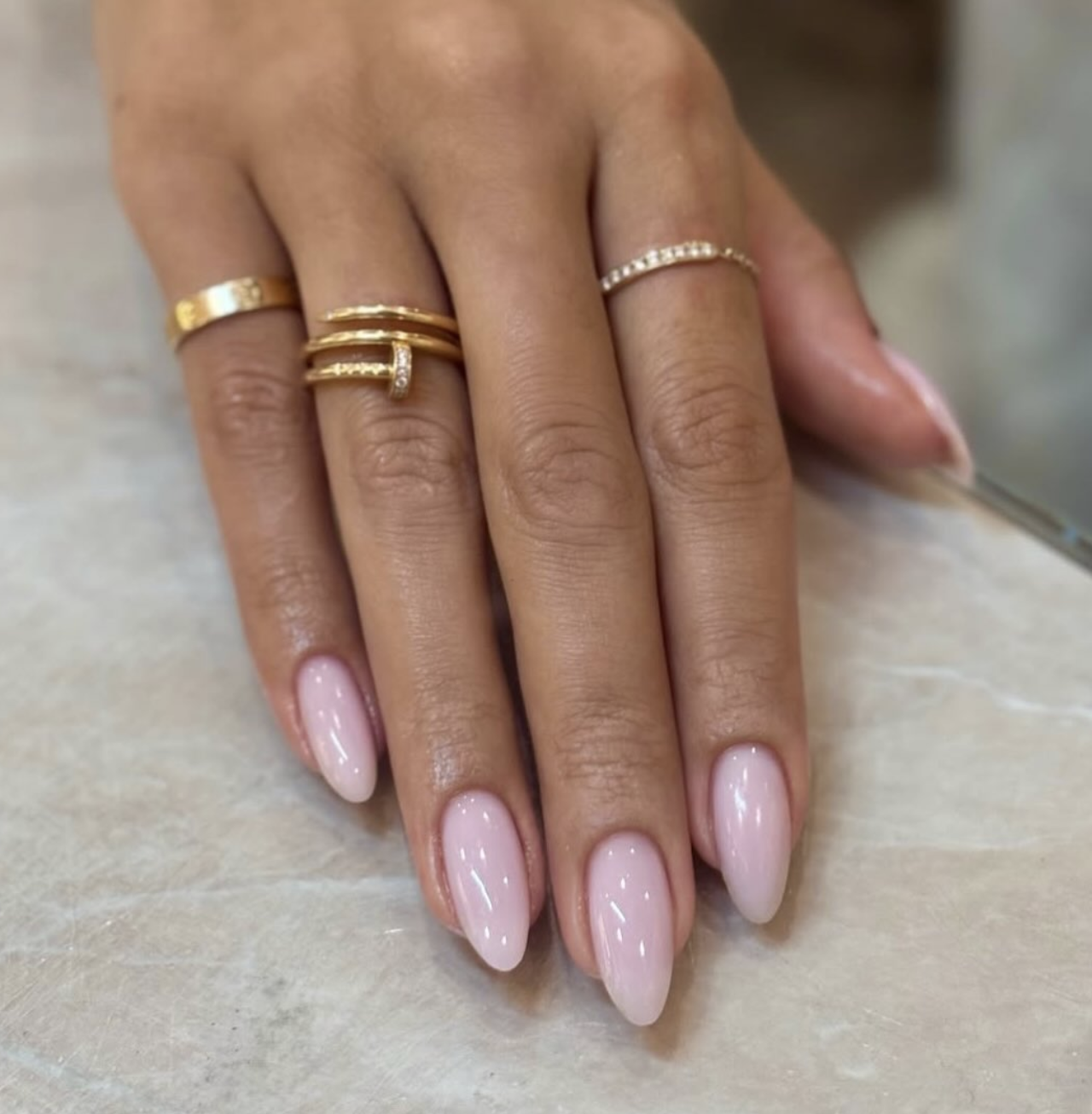Long almond-shaped nails with a glossy, semi-sheer milky pink polish finish, showcasing clean and cute June nail ideas.