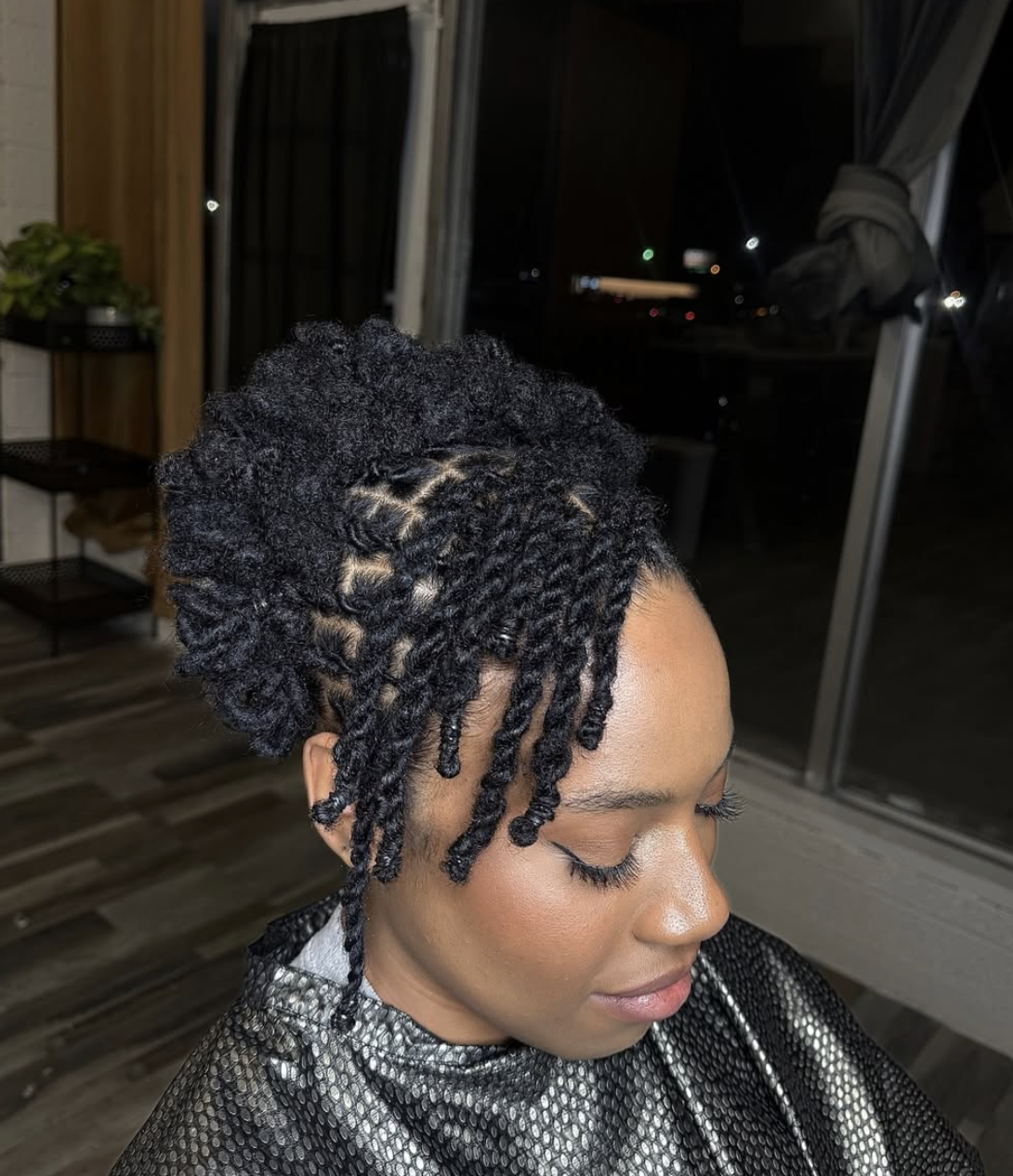 A woman with an oval face shape wearing a high-volume loc updo with soft, curled tendrils framing the face.