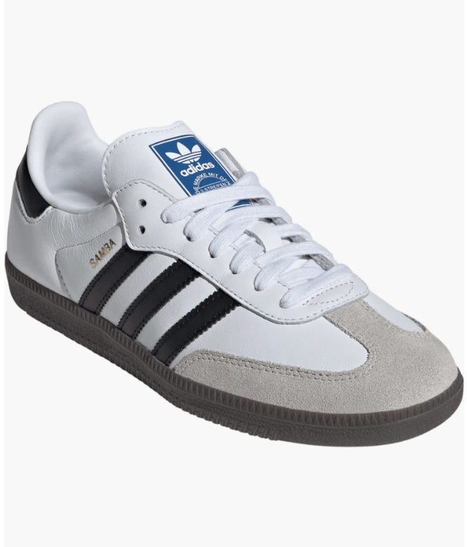 A pair of classic Adidas Samba OG sneakers in white leather with black stripes and a grey suede toe cap, a versatile footwear option for a professional yet casual work capsule wardrobe.