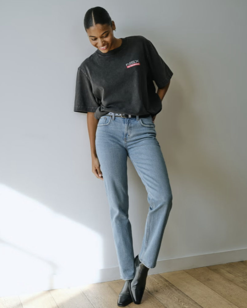 Model wearing Abercrombie Curve Love Mid Rise 90s Straight Jeans in a light wash, styled with black pointed-toe boots to show the gap-free waistband fit on an athletic figure.
