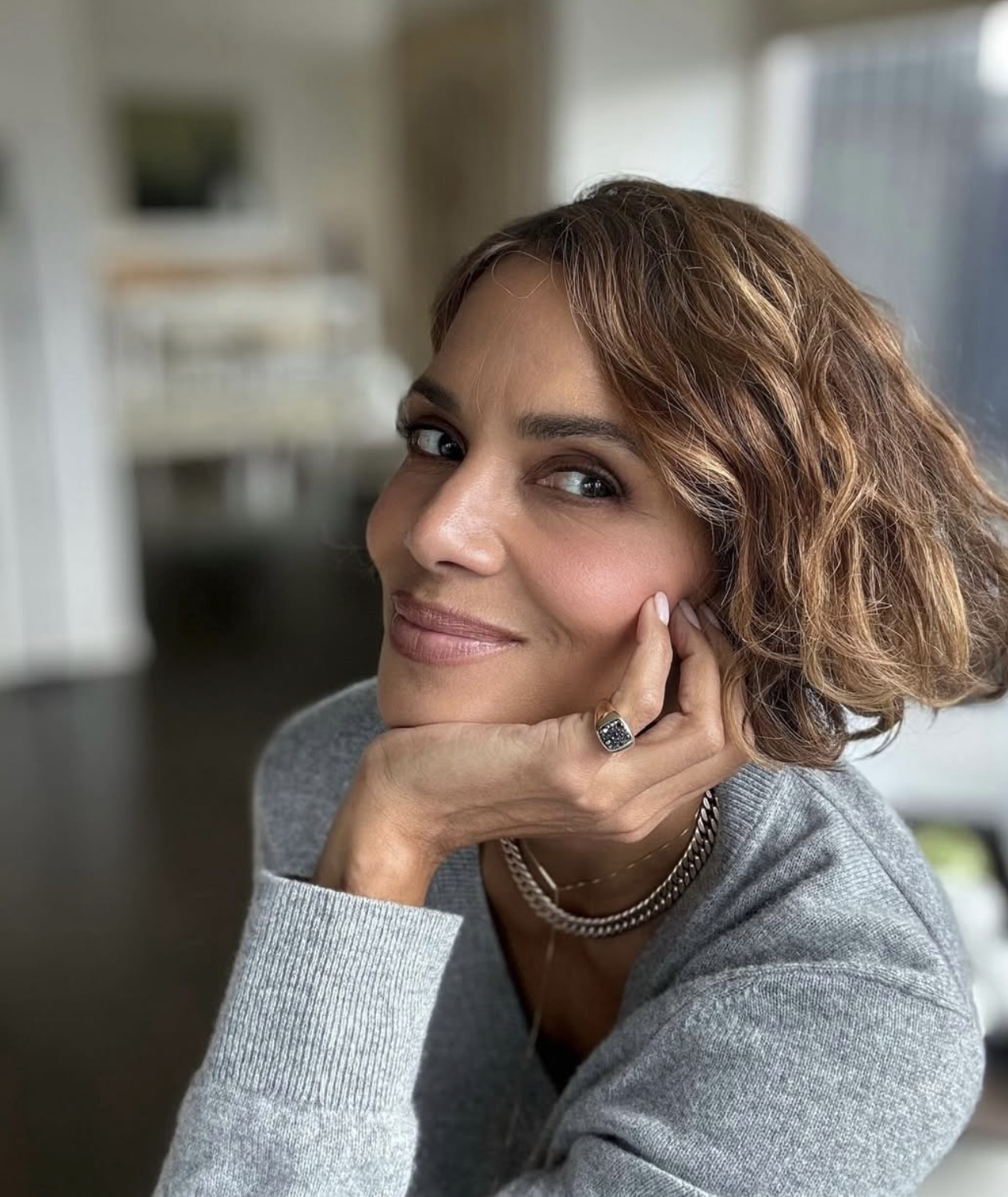 Woman wearing a highlighted wavy bob with a deep side part and softly curved ends.