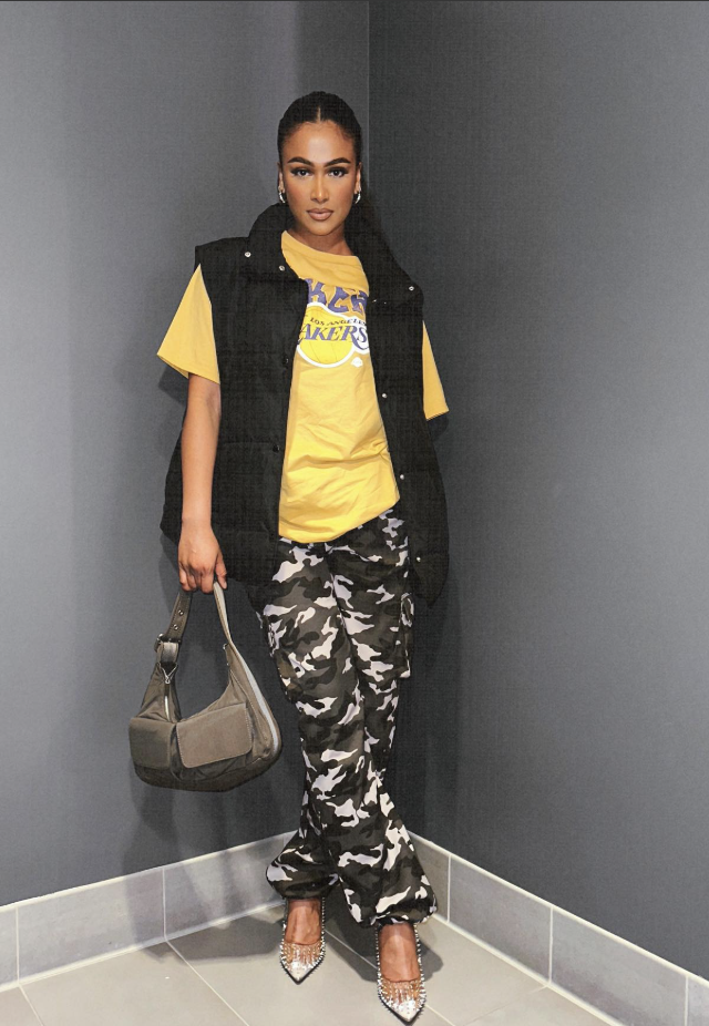 Woman wearing a purple Lakers jacket with high-waisted wide-leg jeans, sunglasses and sneakers.
