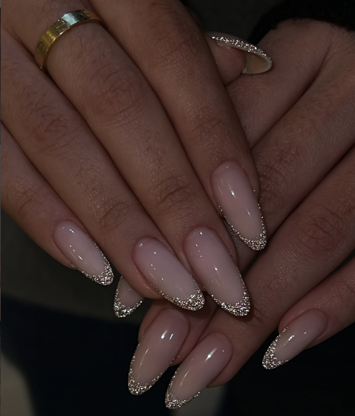 Long, oval-shaped nails showcasing a clean, translucent nude base coat paired with brilliant, reflective silver glitter French tips.