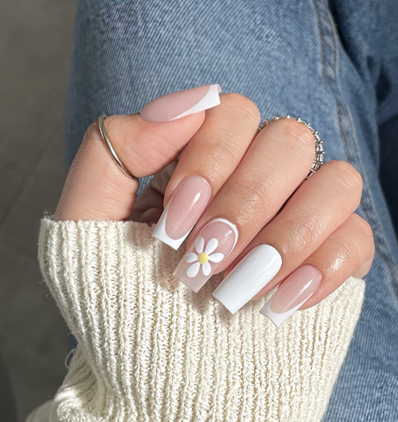Long square-shaped nails featuring classic white French tips and a hand-painted white daisy on the ring finger.