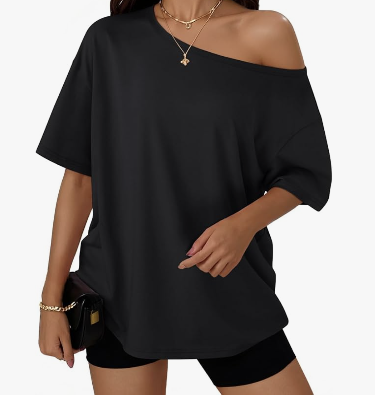 A close-up of a person wearing an oversized black off-the-shoulder short-sleeve t-shirt with a gold necklace and a small black crossbody bag.