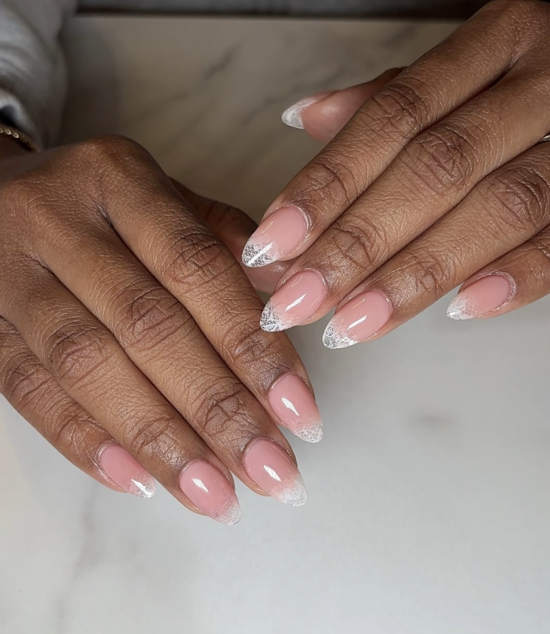 Long coffin-shaped acrylic nails with a black lace pattern over a sheer nude base.