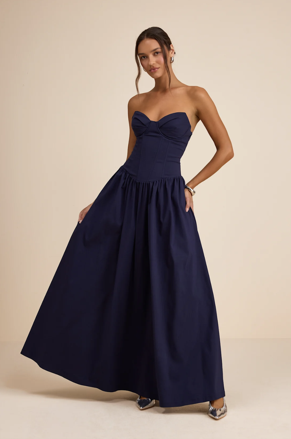 Model wearing the Lulus Almeria Navy Blue Strapless Lace-Up Maxi Dress, featuring a corset-style back for the 2026 romantic heroine trend.