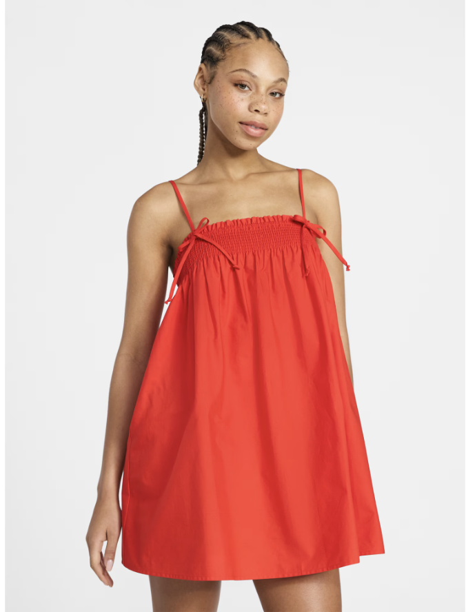A sweet cotton poplin smocked mini dress featuring feminine tie-shoulder straps.
