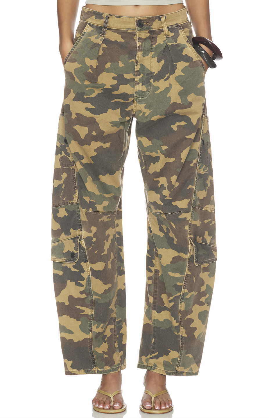A person wearing high-waisted wide-leg cargo pants in a green and brown camouflage print, styled with yellow thong sandals.