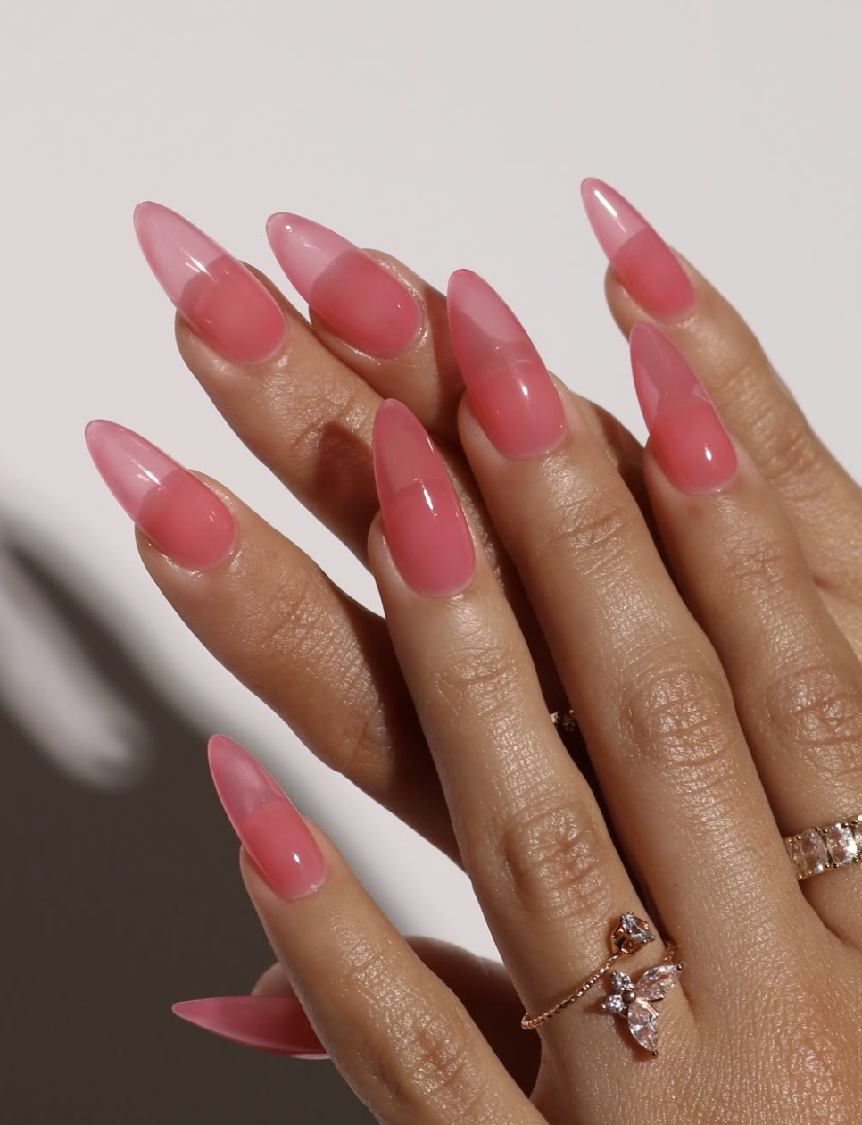 Long almond-shaped nails with a glossy pale pink base, decorated with minimalist hand-painted white and purple daisy flower accents, highlighting cute June nail ideas.