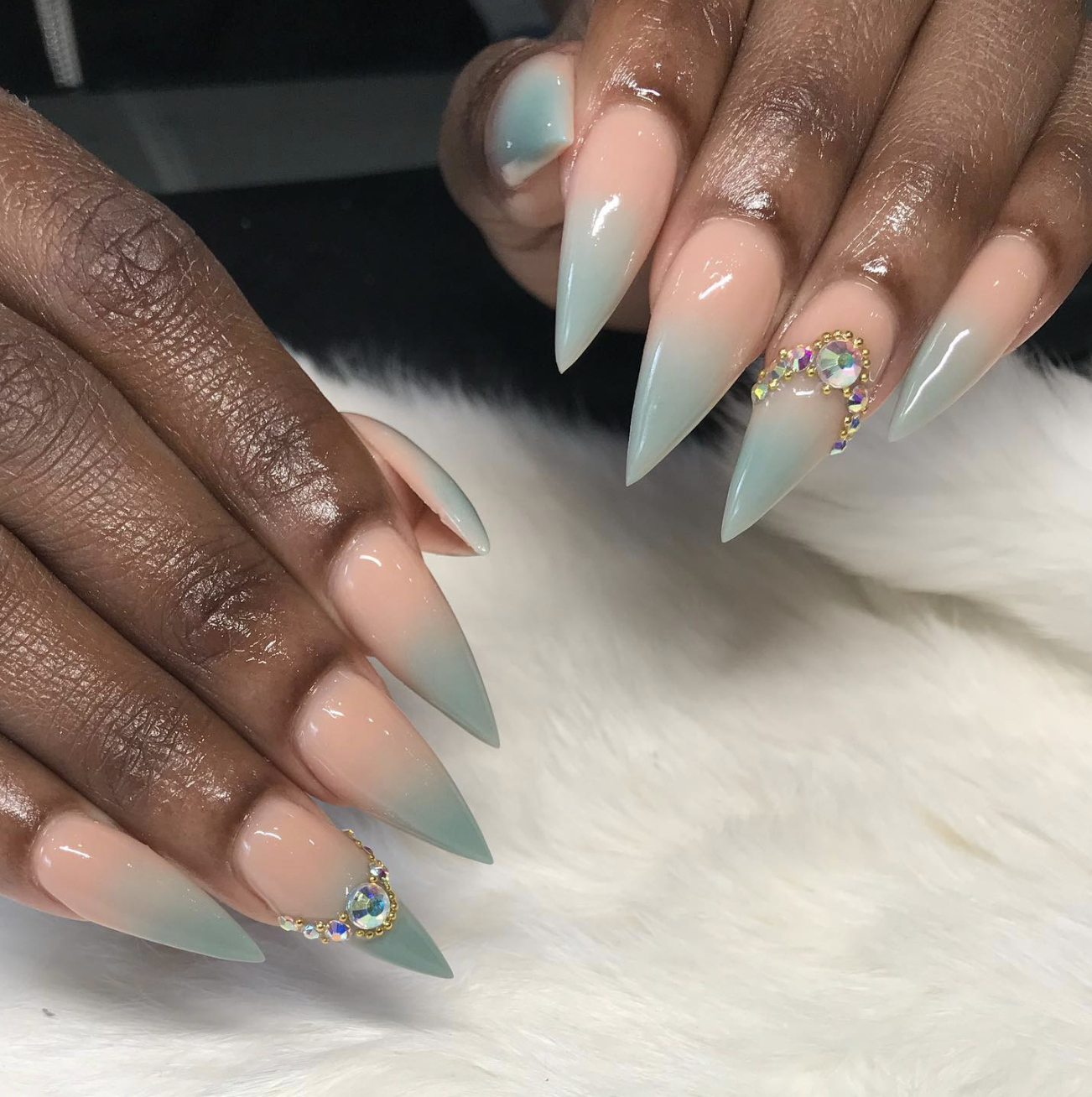 Long stiletto nails with a soft nude base fading into a translucent seafoam green ombré tip, accented with tiny rhinestones at the base, showcasing cute June nail ideas.